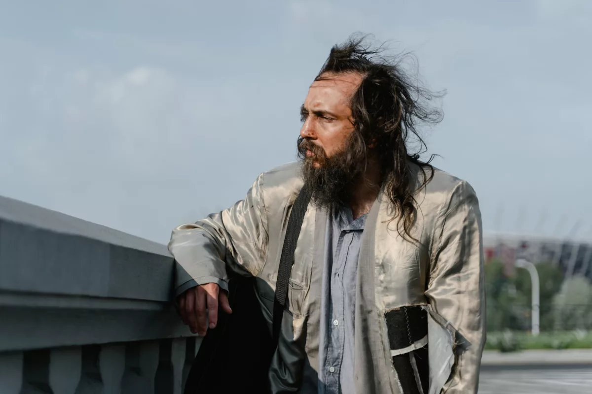 bearded man wearing a ripped gray jacket